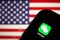 Cellphone with WeChat icon in front of the flag of America.