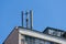 Cellular communication antenna on a flat roof of a multi-storey apartment building against blue sky on a sunny day