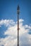 Cellular transmission tower with white clouds and blue sky background.