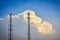 Cellular transmission towers with white clouds and blue sky background.