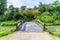 Cement bridge with wooden balustrade over pond to garden