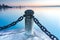 Cement pier post and heavy iron chain links with calm blue water