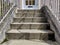 Cement steps leading up to a white door with a mail slot