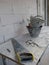 The cement tub, hand saw and broken eyeglasses on dirty work table with  the white bricks wall in construction site of building