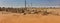 Cemetery at the edge of the village in the desert with a mausoleum in the background and power lines above the graves