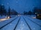 Center of the snowy road with rails. The night city with snowfall.