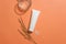 Centered unlabeled white tube with white rice and a glass on an orange background. Embracing a vegan cosmetics concept featuring