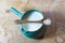 Centered view of blue green ceramic pitcher bowl of rice milk, wooden spoon with rice balanced on top
