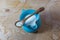 Centered view of a small blue ceramic pitcher of rice milk with wooden spoon of rice on vintage wood table