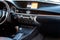 The central console panel inside a black car with wooden and chrome parts, navigator and control buttons, sensors, gearshift lever