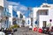 Central street in Mykonos town. Typical white Greek houses with blue doors and windows on a cozy narrow street. Mykonos island,