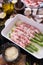 ceramic baking dish with aspargus covered with bacon on wooden kitchen table