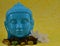 Ceramic Blue color Serene face statue of Buddha with flowers on colorful yellow background