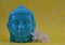 Ceramic Blue color Serene face statue of Buddha with flowers on colorful yellow background