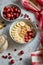 Ceramic bowl of oatmeal porridge with banana, fresh cranberries and walnuts