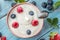 Ceramic bowl with plain yoghurt and berries on the table. Light summer mood