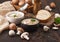 Ceramic bowl plates of creamy chestnut champignon mushroom soup with spoon, pepper and kitchen cloth on dark wooden  background