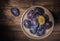 Ceramic bowl with plums over dark wooden board. Fruit background. Top view. Agriculture, Gardening, Harvest Concept.