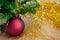 The ceramic Christmas decoration maroon ball with golden tinsel under the Christmas tree