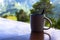 Ceramic cup of coffee on balcony with summer nature background. Relaxing breakfast in mountain lodge