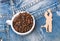 Ceramic cup with coffee beans and wooden silhouette of dancing couple over denim background. Romantic coffee break. Mug