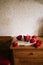 Ceramic cup of fresh hot espresso coffee standing on a pile of books and notebooks on the wooden counter, decorated with red ranun