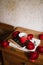 Ceramic cup of fresh hot espresso coffee standing on a pile of books and notebooks on the wooden counter, decorated with red ranun