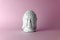 Ceramic head of a Buddha on a pink background. Minimal concept, copy space