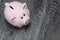 Ceramic piggy bank in the form of a pink pig. Against the background of aged wooden boards with a black structure