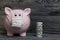 Ceramic piggy bank in pink. With a gauze bandage. In front of her are several dollar bills rolled up into a tube and drunk with