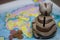 A ceramic piggy bank with a slot for coins is on the world map. Several coins are scattered nearby. Piggy bank for travel