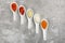 Ceramic spoons with different sauces on grey background, top view