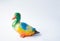 Ceramic statuette of a duck on a white background with brightly colored feathers. Duckling with mother duck