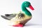 Ceramic statuette of a duck on a white background with brightly colored feathers. Duckling with mother duck