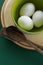 Ceramic tablewares in pastel colors and fresh chicken eggs on deep green background