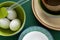 Ceramic tablewares in pastel colors and fresh chicken eggs on deep green background