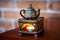 Ceramic teapot and  burning tealight on brown table against brick wall background. Ethereal oils. Cozy, warm and smelling good