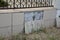 Ceramic tiles fall off concrete fence footing outdoors. A close-up of a wrought iron fence with concrete tiled footing with tiles