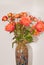 Ceramic vase, filled with four long stemmed, orange roses and a dozen baby, orange and red roses