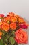 Ceramic vase, filled with four long stemmed, orange roses and a dozen baby, orange and red roses