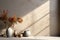 Ceramic vases on the shelf and vase with flowers at beige wall with sun shadows