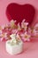 Ceramic white casket with a teddy bear on a background of pink flowers and hearts