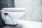 Ceramic white toilet bowl near grey wall, side light in the modern bathroom.
