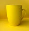 Ceramic yellow cup on a yellow background.