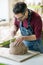 Ceramist Dressed in an Apron Sculpting Statue from Raw Clay in Bright Ceramic Workshop.