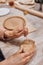 A ceramist in a pottery workshop makes patterns on a clay plate using tools.