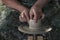 Ceramist with wet hands forms a jug of clay on a rotating potter`s wheel