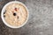Cereal bowl filled with Bircher muesli with blueberries and cranberries on stone kitchen counter