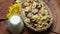 Cereal, dried fruit and jug of milk on wooden table, rotating