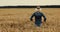 Cereal farming. farmer standing and looking to a crops field. back view